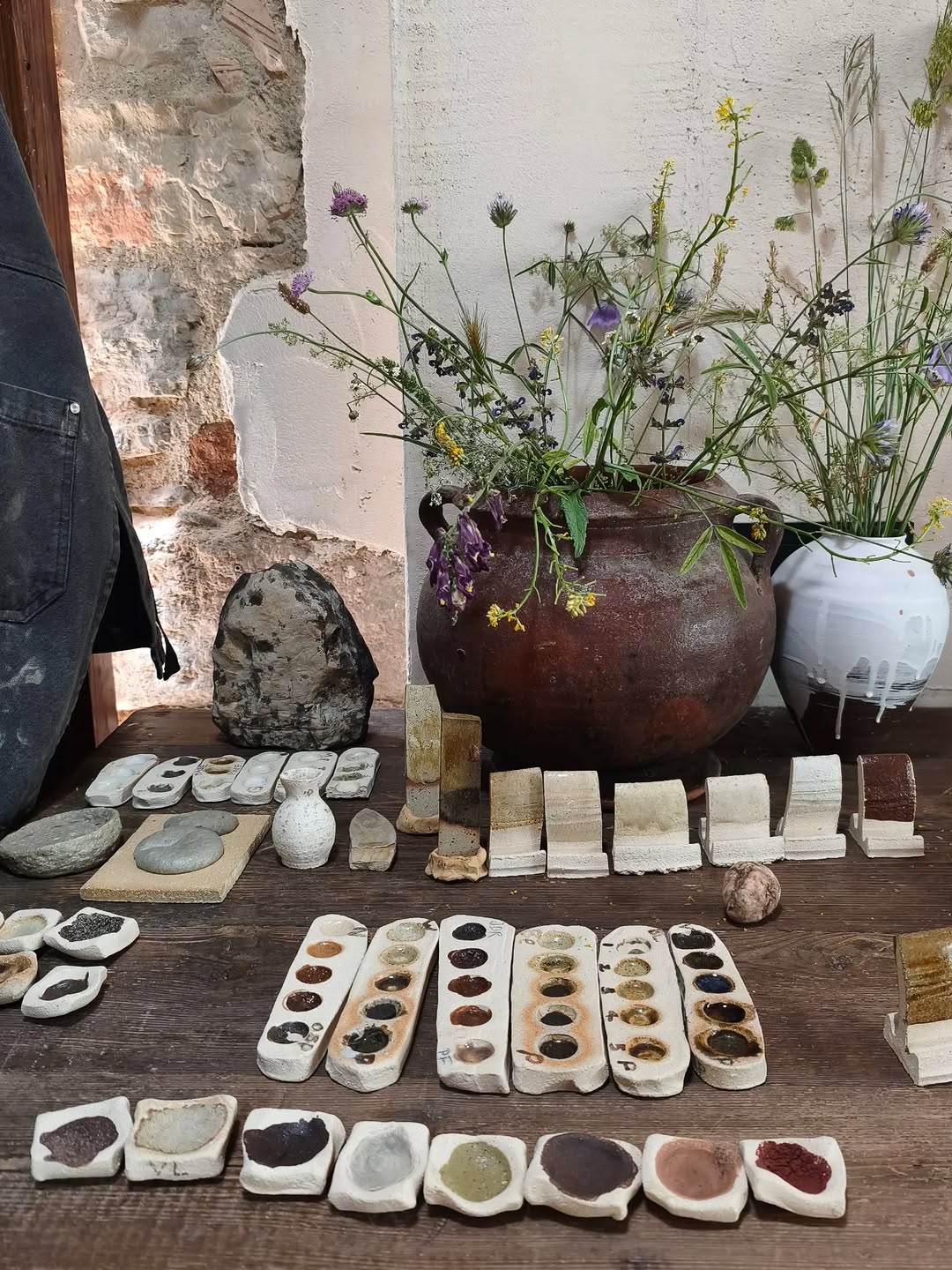 Rows of wild clay and natural glaze tests on the studio workbench.
