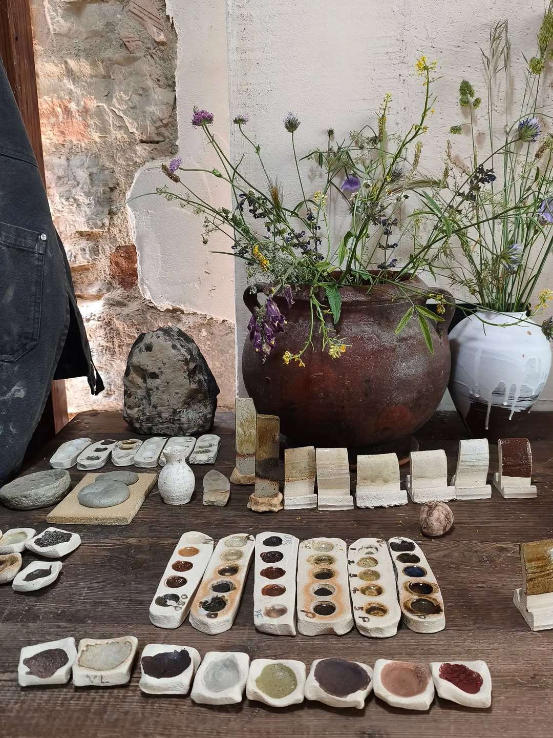 Rows of wild clay and natural glaze tests on the studio workbench.