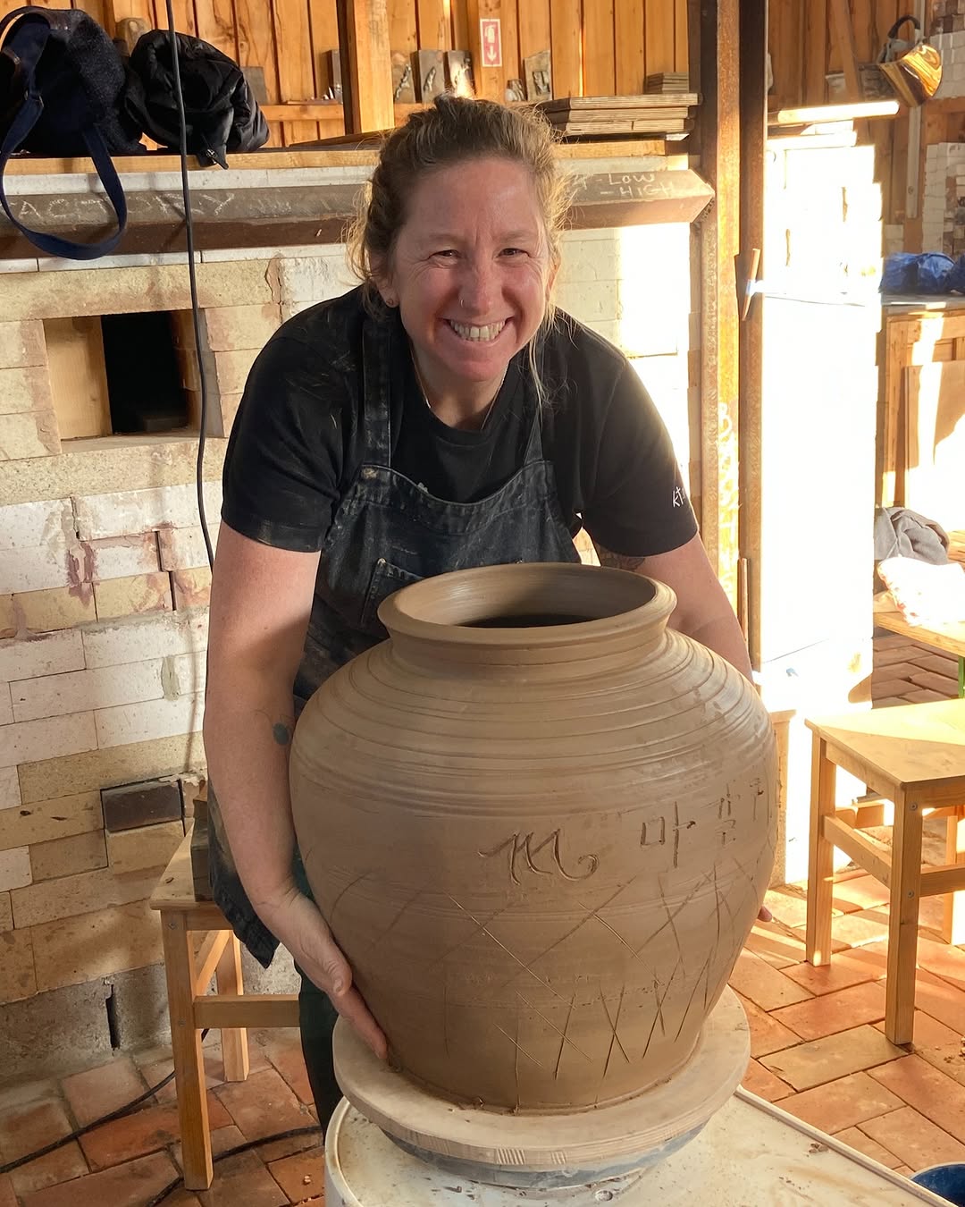 Magali Kivatinetz behind a large freshly thrown jar in the studio.