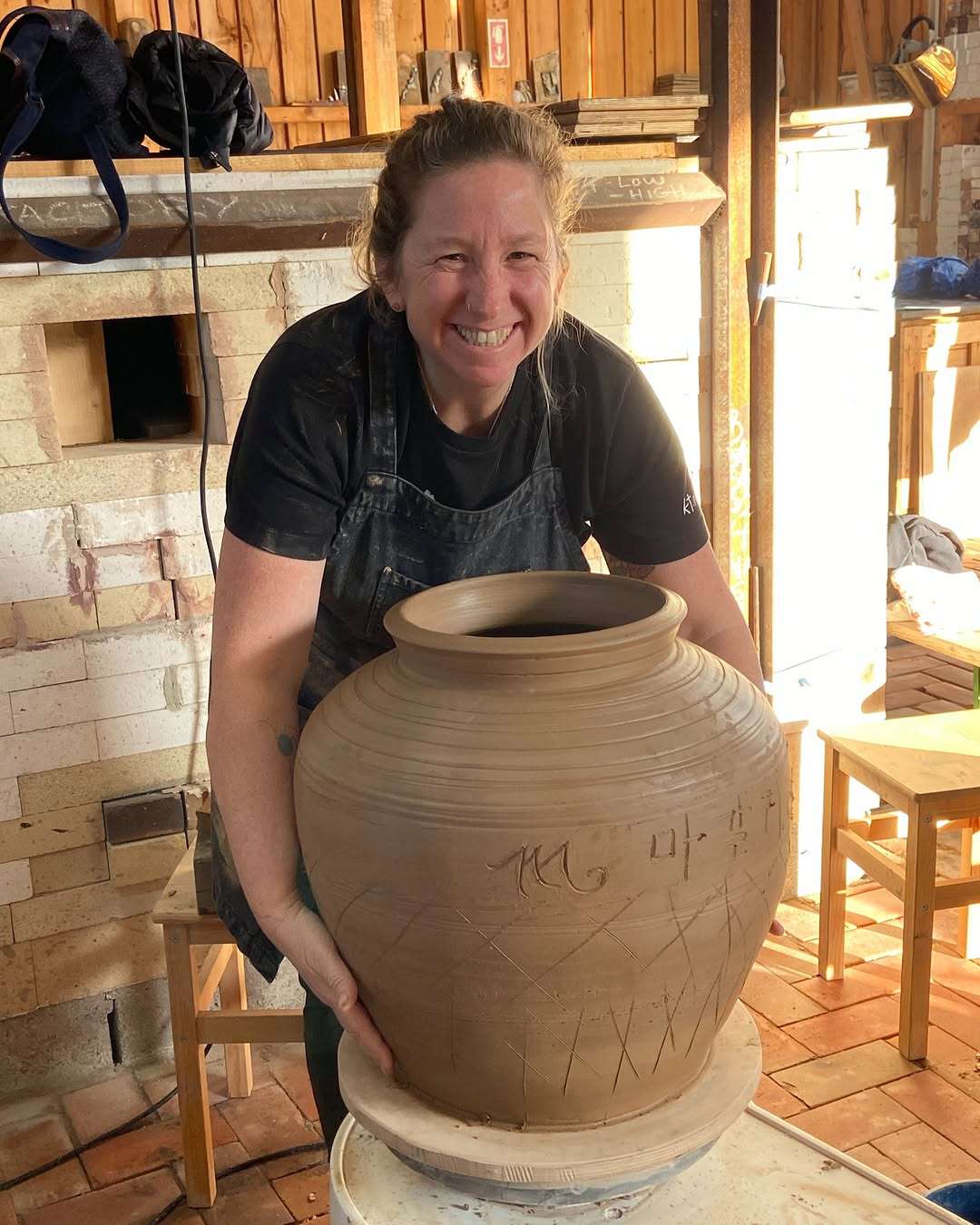 Magali Kivatinetz detrás de una gran tinaja recién torneada en el estudio.