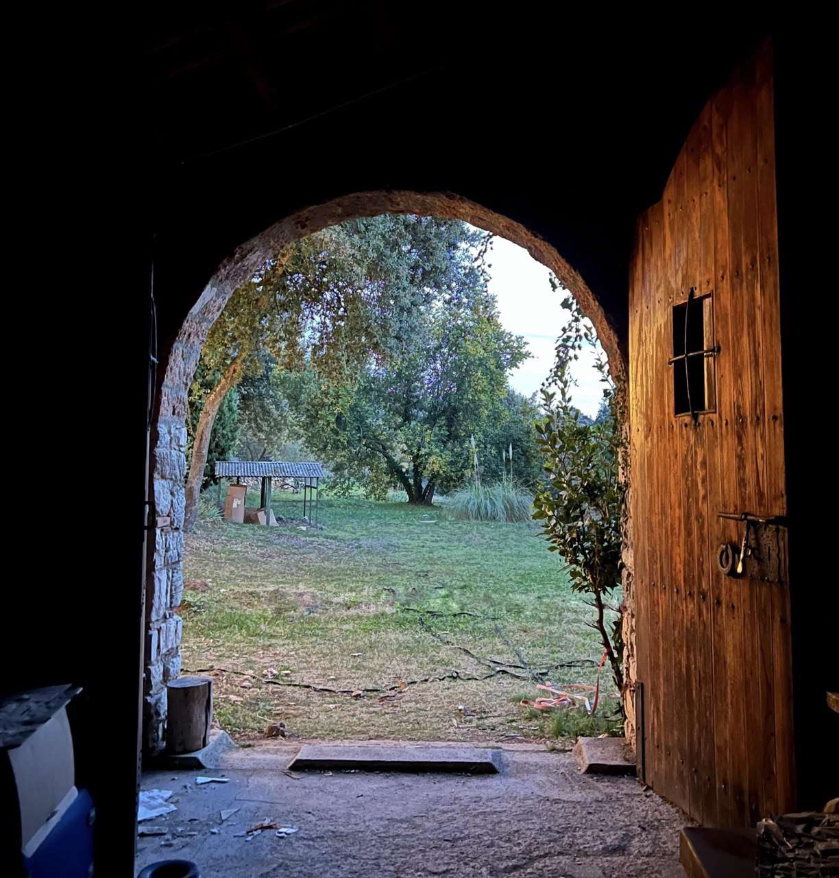 The open wooden door and stone arch at Can Brull, looking out toward the garden.