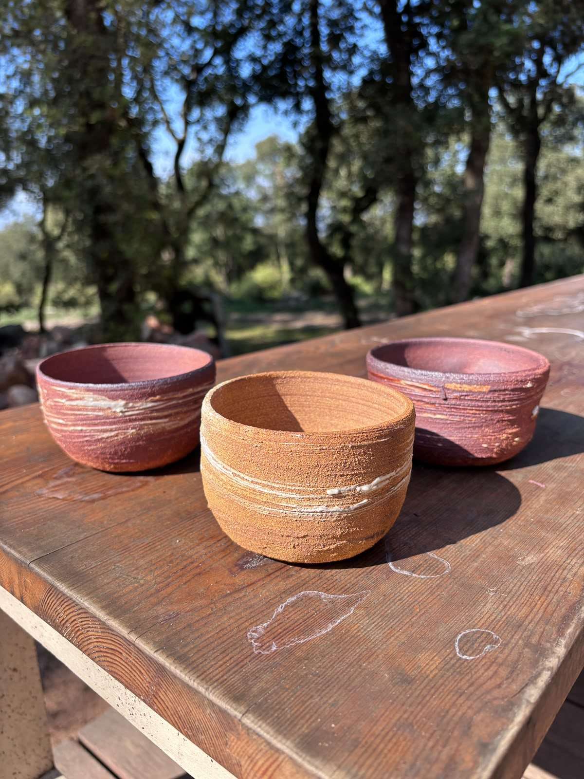 Three wood-fired bowls from Kujiragama on a wooden table.