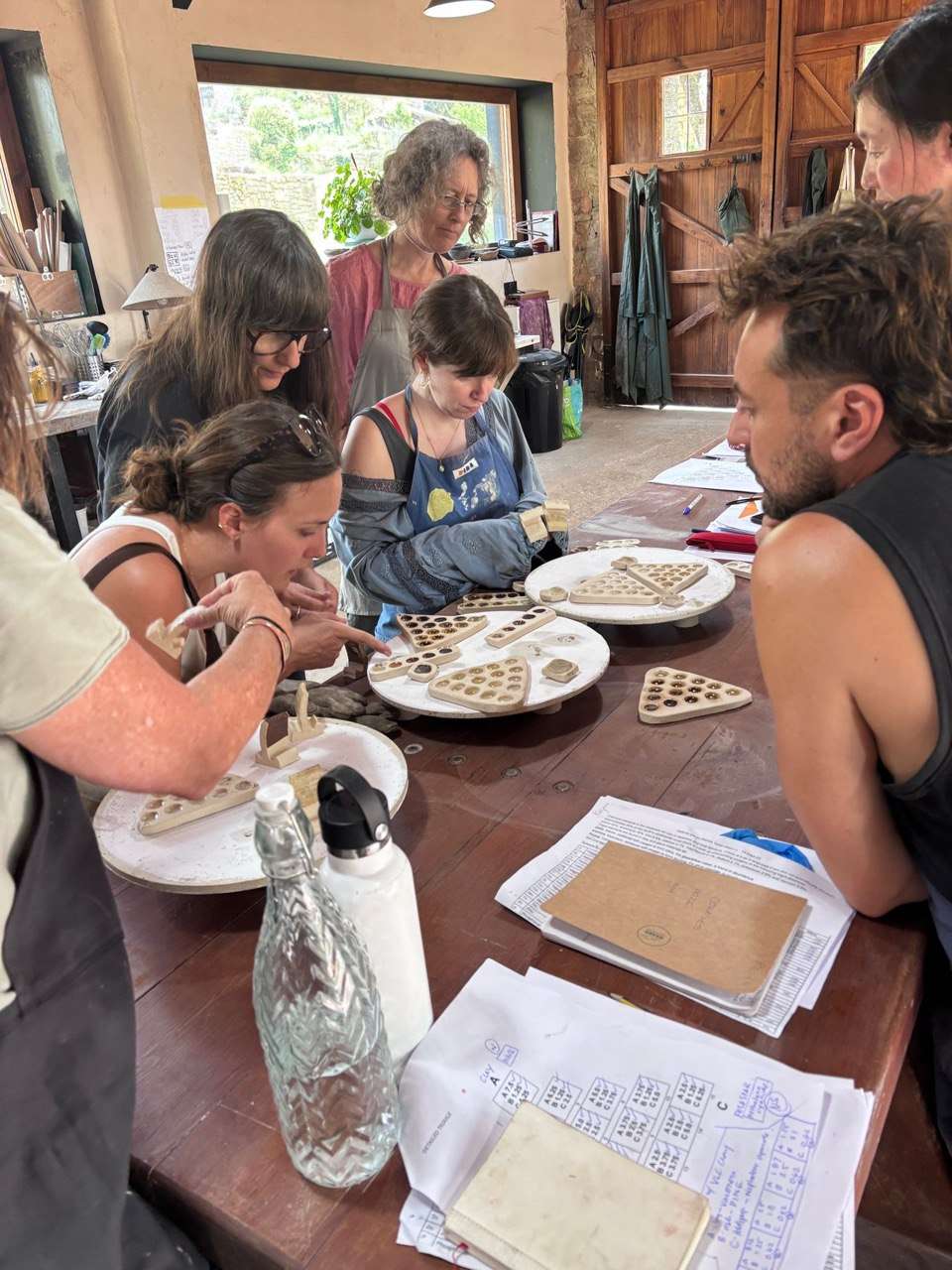 People studying clay and glaze test samples around the studio table.